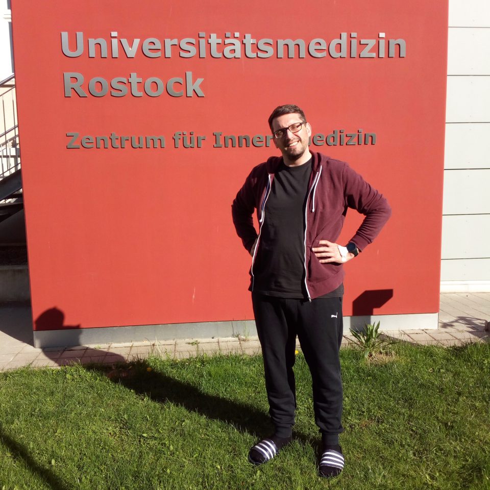 Mann vor einem Schild der Universitätsmedizin Rostock.