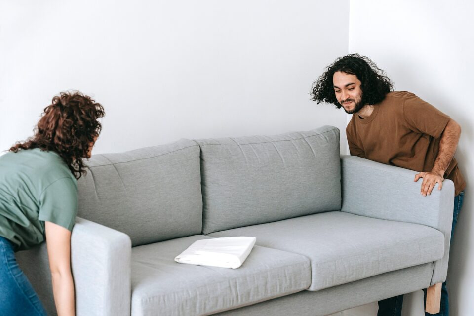 Eine Frau und ein Mann tragen gemeinsam ein Sofa.