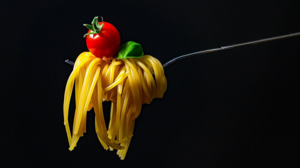 Gabel mit Pasta und einer Tomate darauf