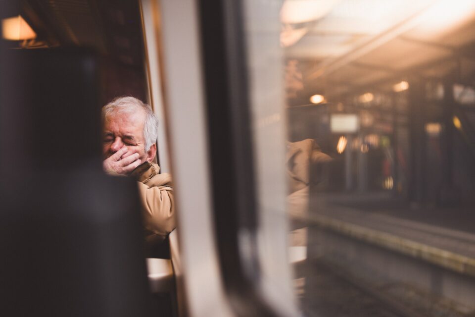 Mann schläft in einem Zugabteil.