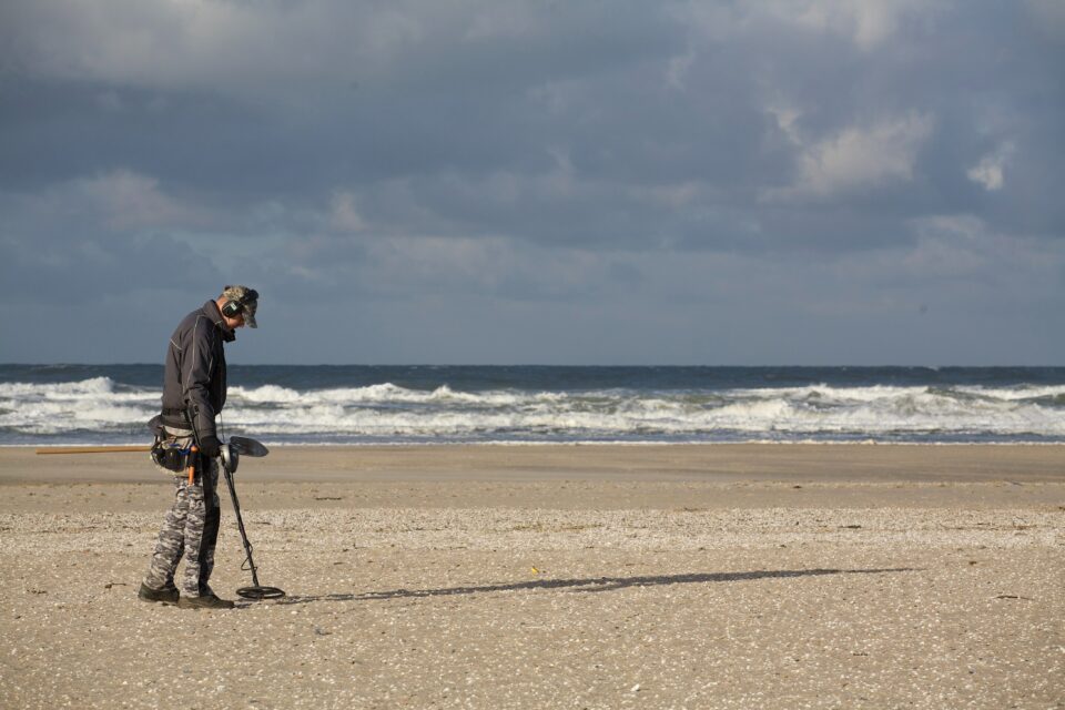 Mann auf einem Strand mit Metalldetektor