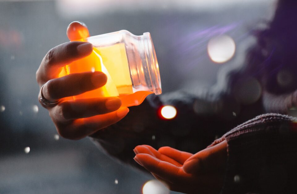 Honig wird aus Glas auf die Hand geschüttet