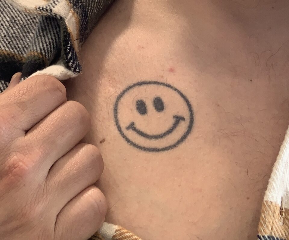 Smiley-Tatto über Carstens Brust