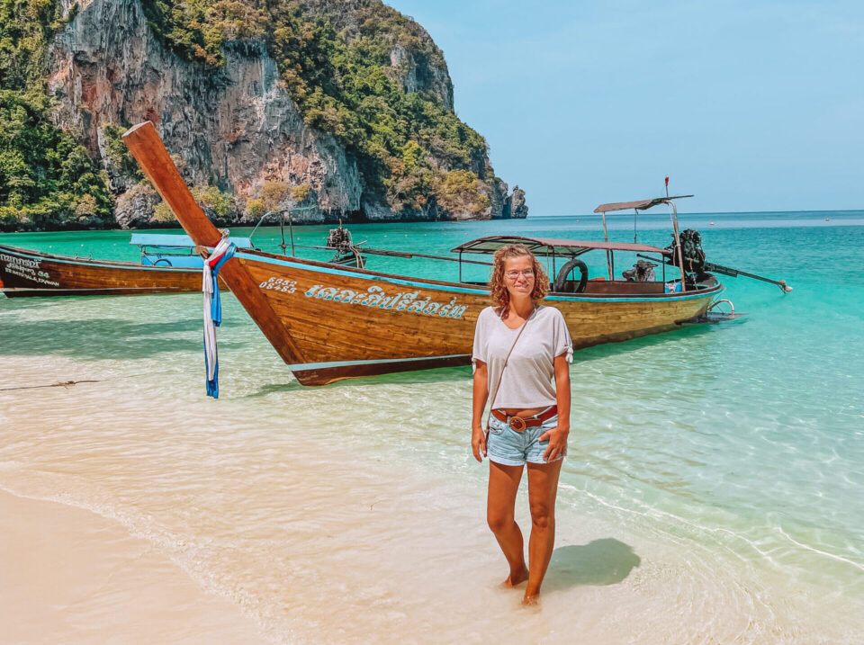 Birgit vor einem Boot am Strand in Thailand