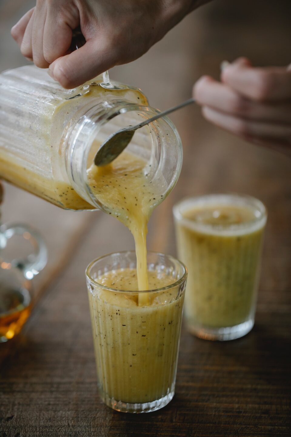 grünlichgelber Smoothie wird in zwei Gläser geschenkt