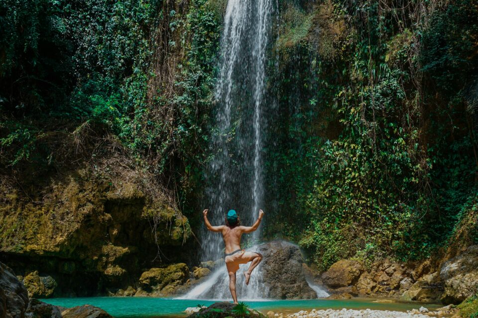 Ein Mann, der auf einem Bein vor einem Wasserfall steht.