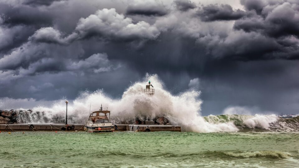 Ein Sturm peitscht eine Welle über die Hafenkante.
