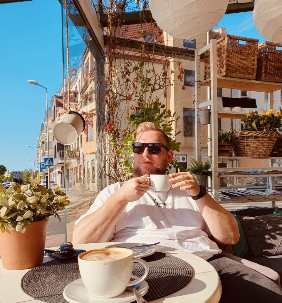 Mann sitzt Draußen und hält Kaffeetasse