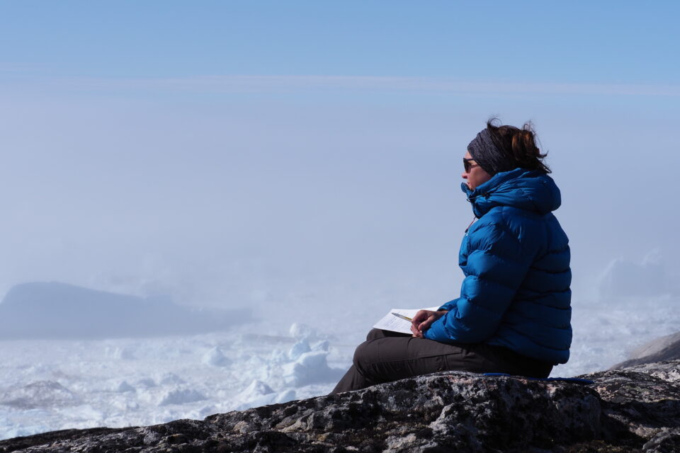 Frau sitz auf hohem Berg Notizblock auf den Beinen