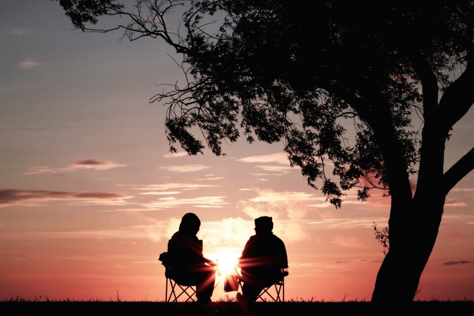 Menschen sitzen Sonnenuntergang