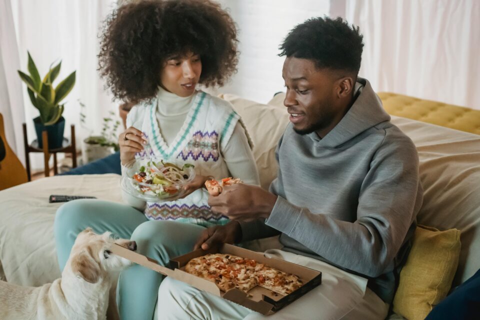 Mann und Frau sitzen auf Sofa mit Pizza