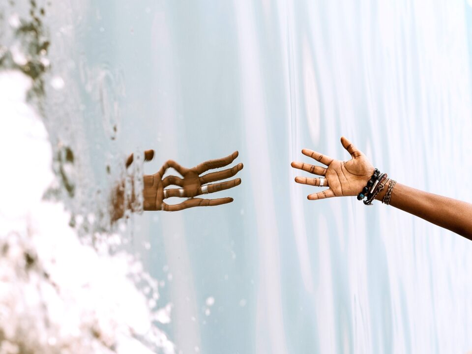 Hand greift nach Spiegelbild Hand im Wasser