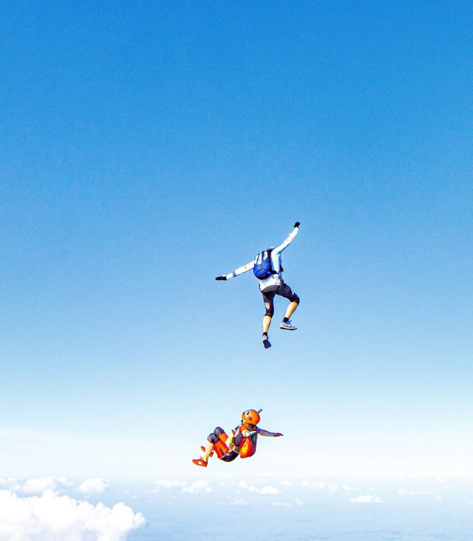 2 Personen mit Fallschirmsack auf Rücken fallend